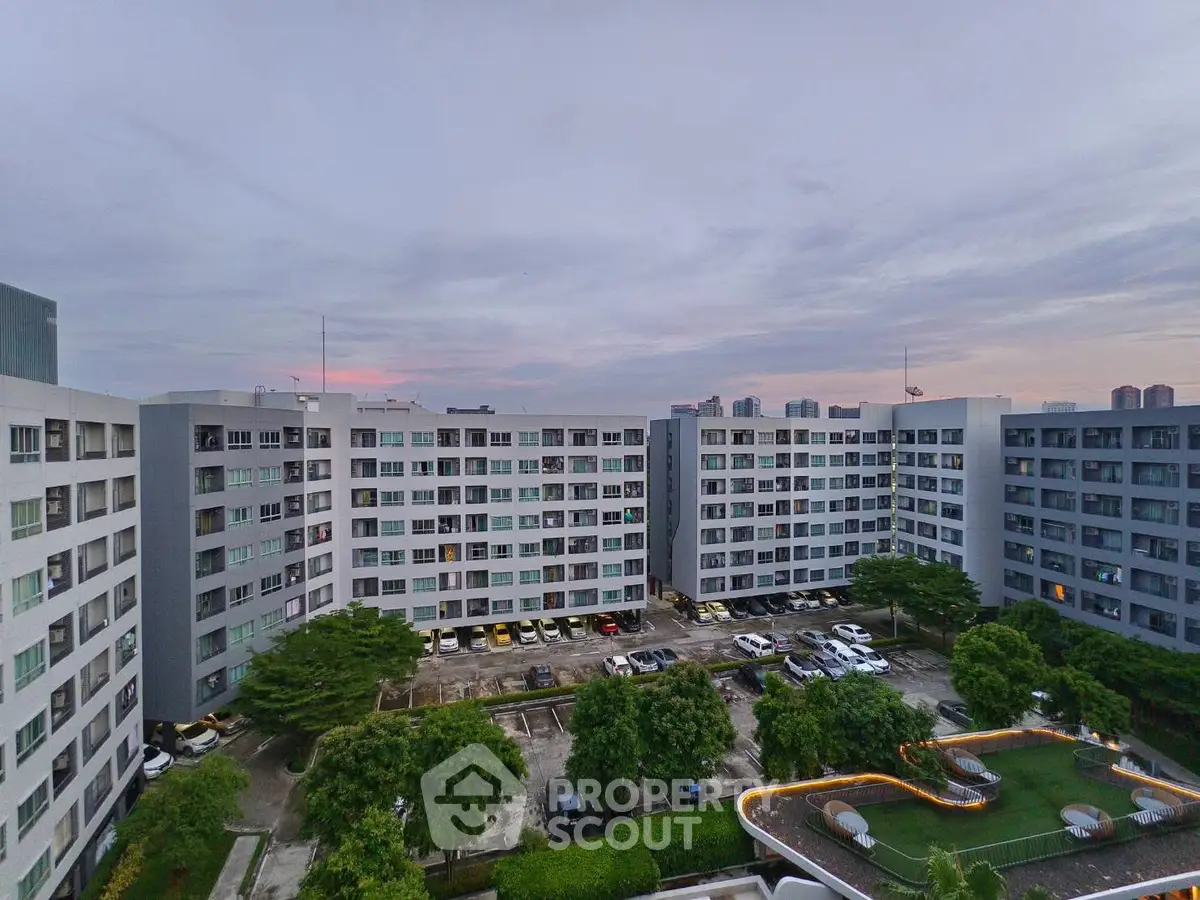 Stunning urban apartment complex with lush greenery and ample parking at dusk.