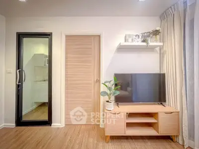 Modern living room with sleek TV stand and glass door to kitchen