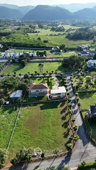Aerial view of a spacious countryside property with lush greenery and scenic mountain backdrop.