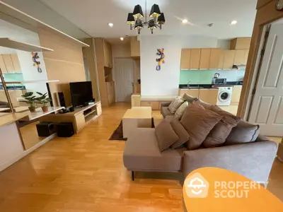 Modern open-plan living room with kitchen, featuring stylish decor and wooden flooring.