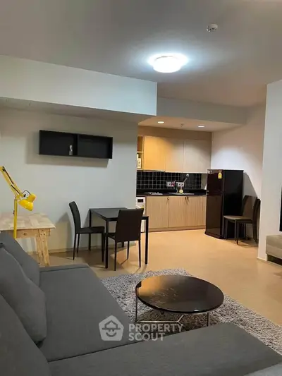 Modern open-plan living room with kitchen, featuring sleek furniture and stylish decor.