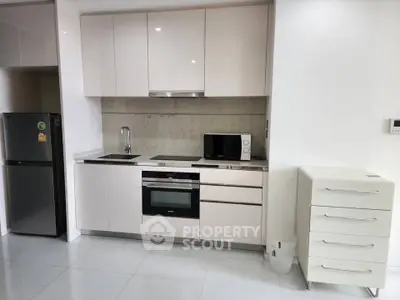Modern kitchen with sleek cabinetry, built-in oven, and microwave in a stylish apartment.