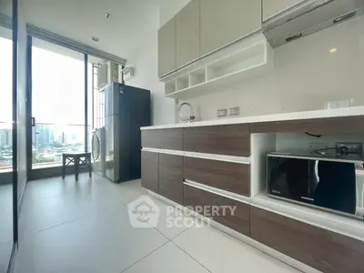 Modern kitchen with sleek cabinetry, large fridge, and city view from window.