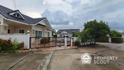 Charming suburban house with gated driveway and lush greenery in tranquil neighborhood.