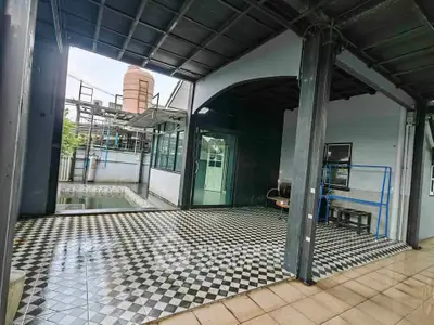 Spacious covered outdoor area with checkered flooring and water tank view.