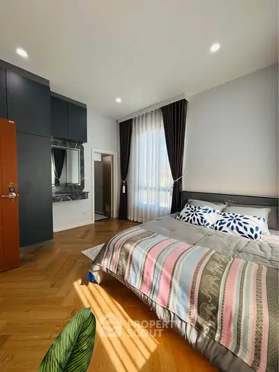 Spacious bedroom with elegant decor and natural light, featuring a cozy bed and stylish curtains.