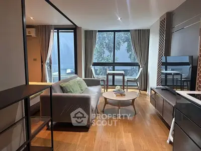 Modern living room with large windows, stylish furniture, and wooden flooring.