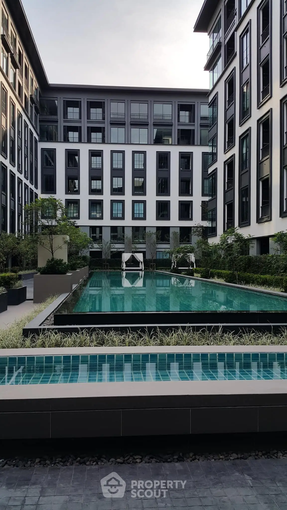 Luxurious modern apartment complex with stunning pool and lush greenery