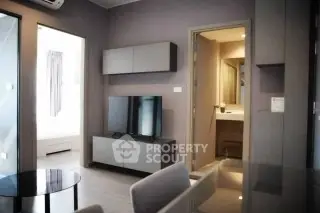 Modern living room with sleek furniture and TV, adjacent to a stylish bathroom.