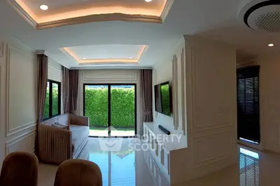 Elegant living room with modern decor and large windows overlooking lush greenery.
