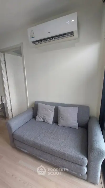 Cozy living room with modern gray sofa and air conditioning unit.