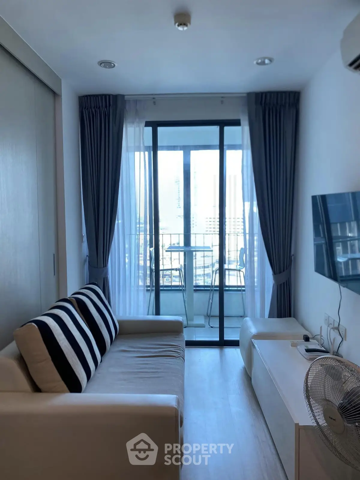 Modern living room with balcony view, featuring sleek furniture and floor-to-ceiling windows for natural light.