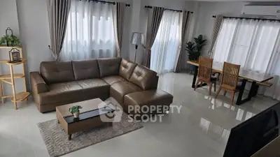 Spacious modern living room with elegant brown leather sofa and dining area, perfect for family gatherings.