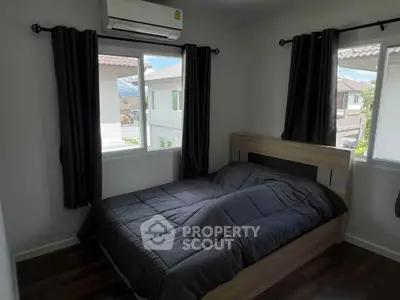Cozy bedroom with modern design and natural light from two windows.