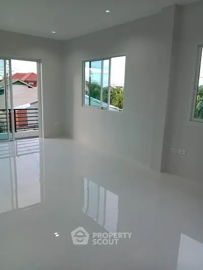 Spacious and bright living room with large windows and glossy white flooring.