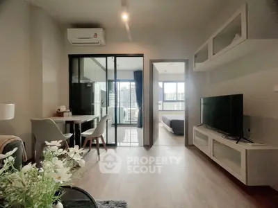 Modern apartment with open living area and city view, featuring sleek furniture and natural light.