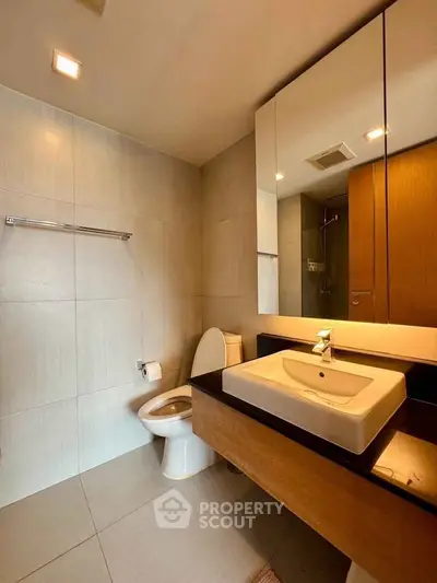 Modern bathroom with sleek fixtures and large mirror in a contemporary home.