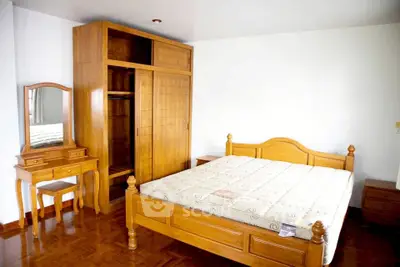 Spacious bedroom with wooden furniture and parquet flooring, perfect for cozy living.