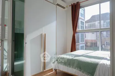 Bright bedroom with large window and modern wardrobe in a stylish apartment.