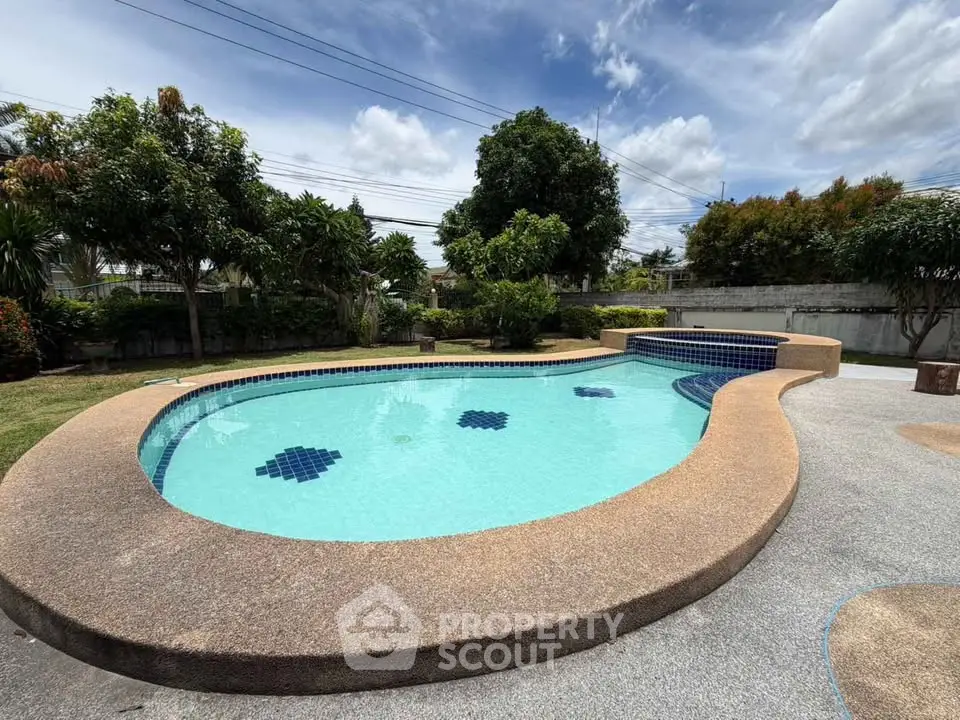 Stunning outdoor pool with lush greenery and clear blue skies, perfect for relaxation and entertainment.
