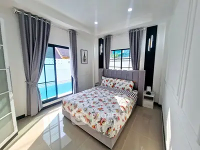 Bright and modern bedroom with pool view, featuring elegant decor and ample natural light.