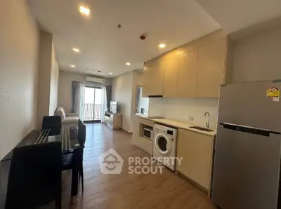 Modern apartment interior with open kitchen and living area, featuring wooden flooring and natural light.