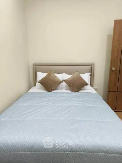 Cozy bedroom with a neatly made bed and soft pillows, perfect for relaxation.