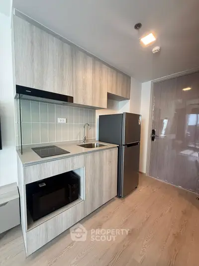 Modern compact kitchen with sleek cabinetry and stainless steel appliances in a stylish apartment.