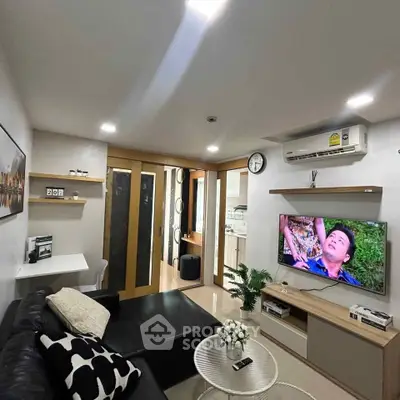 Modern living room with sleek furniture and wall-mounted TV in a cozy apartment.