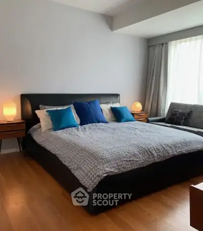 Spacious bedroom with modern decor and large windows for natural light.
