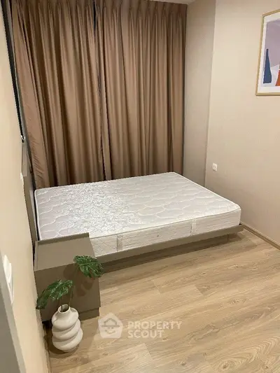 Cozy bedroom with minimalist decor and natural light, featuring a comfortable bed and stylish flooring.