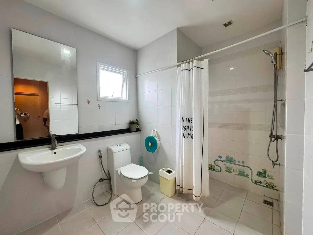 Spacious modern bathroom with shower and sleek fixtures in a contemporary home.