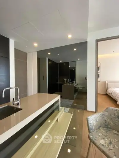 Modern open-plan kitchen with sleek design and adjacent cozy bedroom in a stylish apartment.
