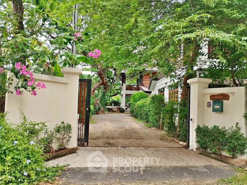 Charming garden entrance to a serene residential property with lush greenery and inviting pathway.