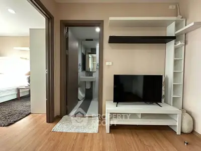 Modern apartment interior with TV unit and bathroom view, showcasing stylish living space.