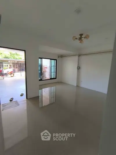 Spacious unfurnished living room with large windows and outdoor access, perfect for customization.