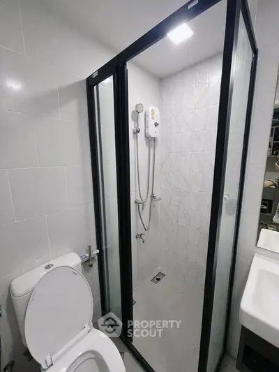 Modern bathroom with glass shower enclosure and sleek white fixtures.