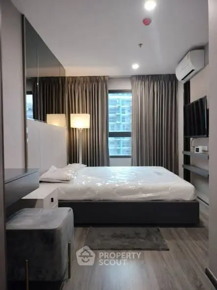 Modern bedroom with sleek design, featuring a large bed, stylish lighting, and a wall-mounted TV.