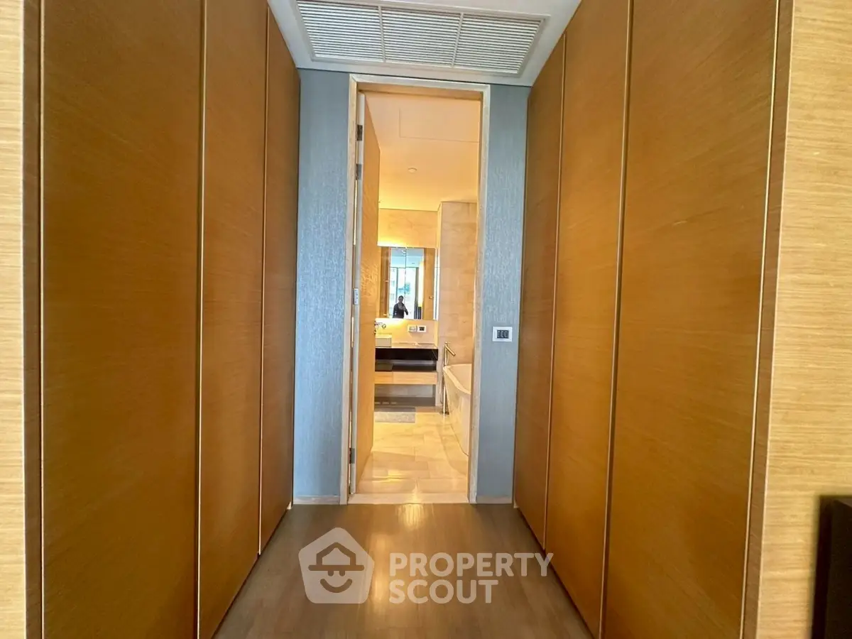 Elegant hallway leading to a luxurious bathroom with wooden accents and modern design.
