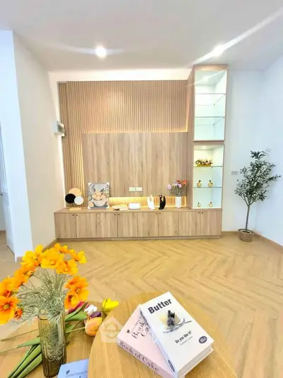 Modern living room with stylish wooden paneling and decorative shelves, featuring vibrant flowers and books.
