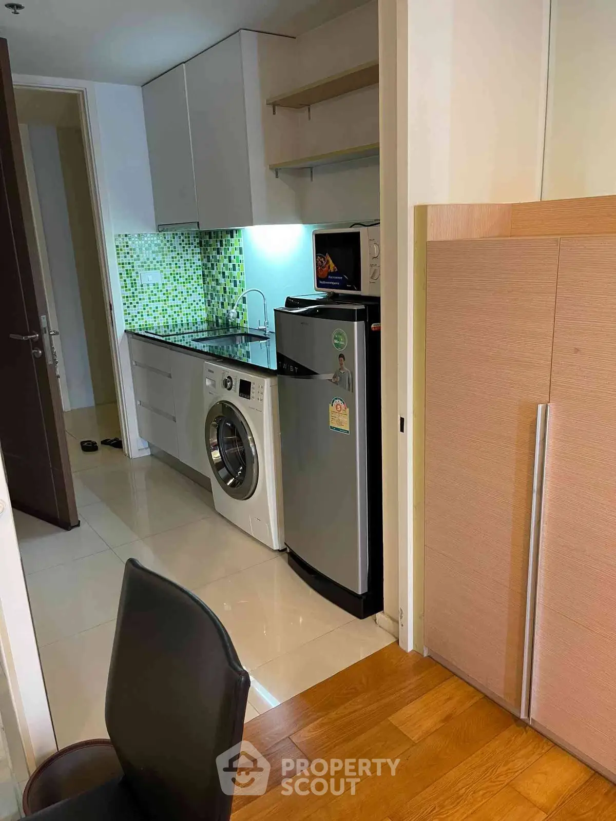 Modern kitchen with washing machine and fridge in compact apartment