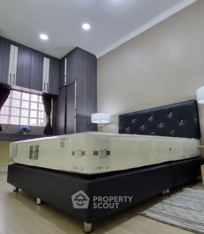 Spacious bedroom with modern furniture and ample storage space, featuring a comfortable bed and stylish decor.