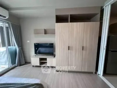 Modern bedroom with sleek wardrobe and TV unit, featuring large windows for natural light.