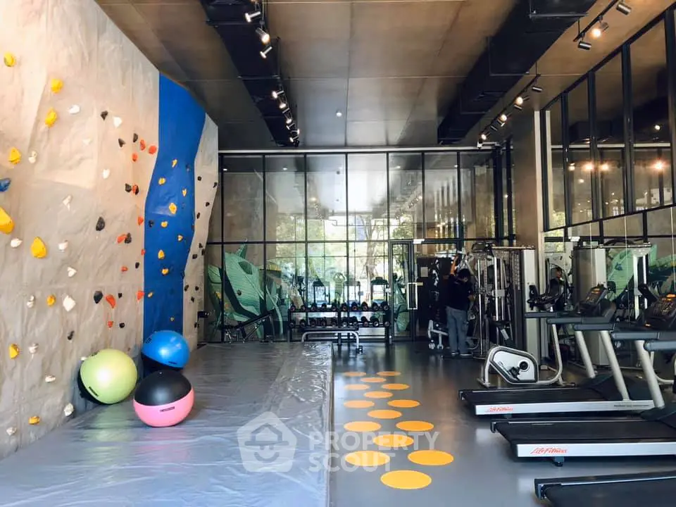 Modern gym with climbing wall and fitness equipment in luxury apartment building.