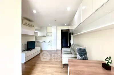 Modern living room with sleek furniture and open kitchen layout in a bright apartment.