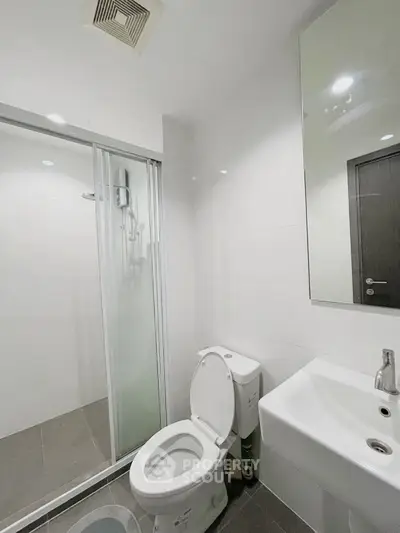 Modern bathroom with glass shower and sleek fixtures in contemporary home.