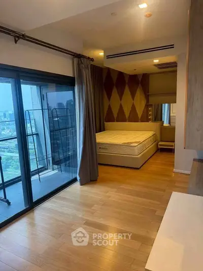 Spacious bedroom with floor-to-ceiling windows and city view, featuring modern decor and wooden flooring.