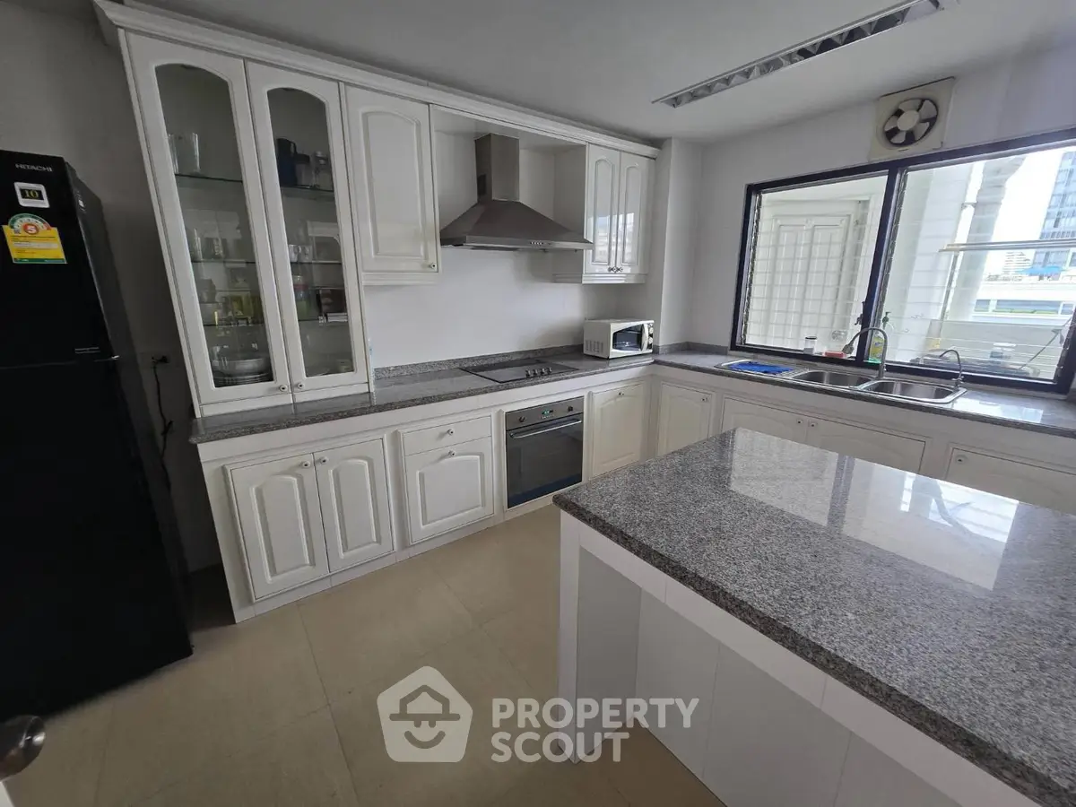 Spacious modern kitchen with granite countertops and built-in appliances in a bright apartment.