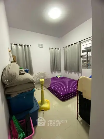 Cozy bedroom with minimalist decor and natural light, featuring a comfortable bed and practical storage solutions.