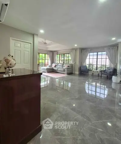 Spacious living room with elegant marble flooring and large windows for natural light.
